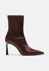 Braune Satin-Stiefelette mit spitzem Zehenbereich und schlankem hohen Absatz auf einem einfarbigen hellgrauen Hintergrund.