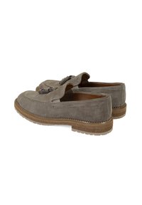 Een paar grijze suede tassel loafers met bruine gestructureerde zolen, gestikt detail en slip-on ontwerp, weergegeven op een witte achtergrond.