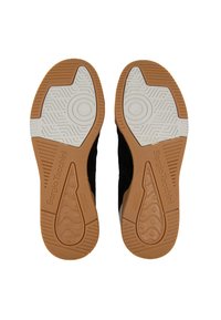 Suole di sneakers nere in suede con gomma naturale texturizzata e accenti bianchi. Presenta motivi circolari e branding nel design.