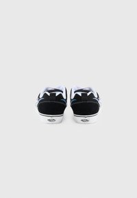 Sorte semskede sneakers med hvite såler, blå aksenter og polstret krage. Har et signaturmerke på hælen og kontrastsøm.