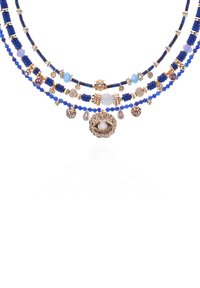 Collier à plusieurs couches avec des perles bleues, des accents dorés et un pendentif avec un design d'œil central. Comprend des éléments décoratifs et des textures variées.