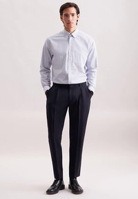 Lichtblauw geruit overhemd met knopen, donker gesneden broek en zwarte nette schoenen. Glad materiaal, gestructureerde pasvorm, minimalistisch ontwerp.