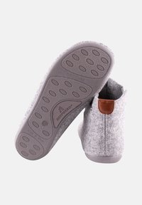 Chaussons en feutre gris avec une semelle en caoutchouc, présentant un accent en cuir marron au niveau du talon. Design simple adapté à une utilisation intérieure.