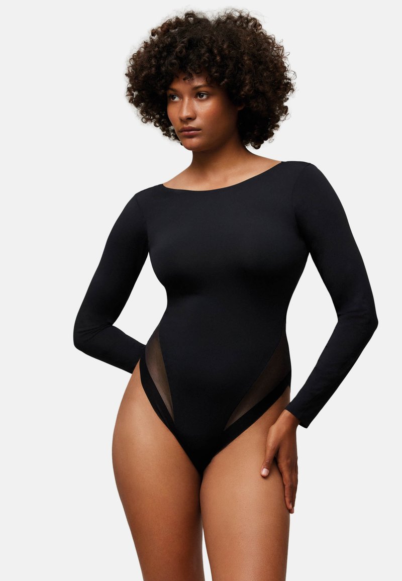 Body negro de manga larga hecho de tela suave, con detalles de malla transparente en los costados y cuello redondeado.
