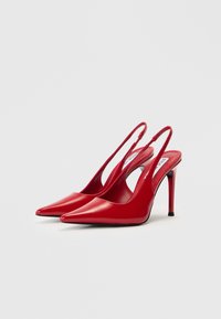 Κόκκινα ψηλοτάκουνες γόβες slingback από δερμάτινο λουστρίνι, με μυτερή μύτη και λεπτούς τακουνάκια στιλέτο. Διαθέτουν κοψίματα στα πλάγια και μινιμαλιστικό σχέδιο.