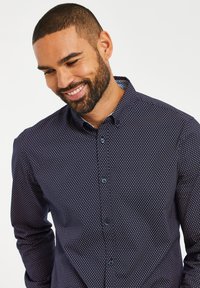 Navyblaues Hemd mit geometrischem Muster in Hellblau und Weiß. Verfügt über einen klassischen Kragen und lange Ärmel mit Knopfmanschetten.