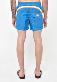 Costume da bagno blu con cordoncino, caratterizzati da strisce laterali arancioni e gialle e una tasca posteriore con un'etichetta logo. Materiale liscio e leggero.