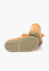 Scarpe slip-on arancioni in canvas con suole in gomma texture, dotate di cuciture e un accento in corda intrecciata intorno alla base.