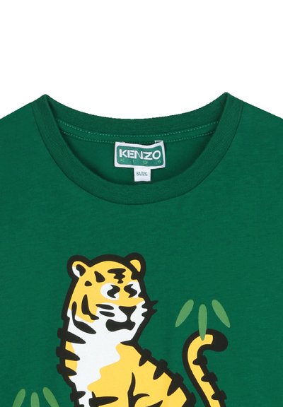 T-shirt en coton vert avec un graphisme de tigre en jaune et noir, des accents en bambou vert et un col rond. Étiquette KENZO Kids visible.