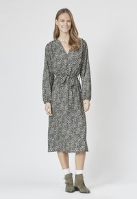 Kjole i mid længde med leopardprint, der har lange ærmer, en bindebælte i taljen og en v-udskæring. Lavet af let, flagrende stof.