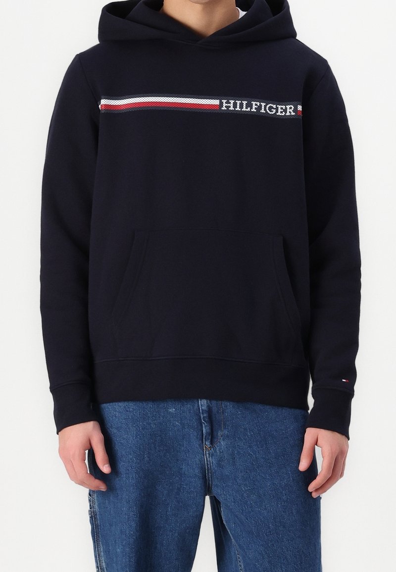 Felpa blu navy con tasca a marsupio frontale, design decorativo a righe rosse e bianche, e logo "HILFIGER" ricamato sul petto.