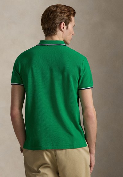 Πολό μπλούζα σε πράσινο χρώμα με κοντά μανίκια, με υφή υφάσματος, κλασικό γιακά και αντίθετη ναυτική ρίγα κατά μήκος του γιακά και των μανικιών.