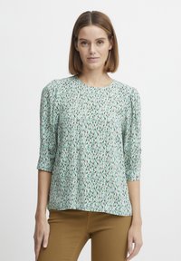 Lichte, gedessineerde blouse met een groen-wit bladmotief. Het heeft driekwartmouwen en een ronde halslijn, met een relaxte pasvorm.
