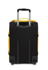 Maleta con ruedas negra y amarilla, con un asa retráctil, textura suave, base reforzada y asas laterales de transporte.
