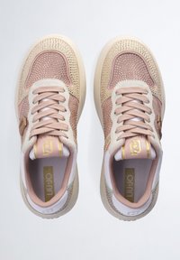 Les baskets présentent une tige en mesh rose clair avec des perforations, des accents crème et des éléments métalliques dorés. Les lacets et le rembourrage coordonnés complètent le design.