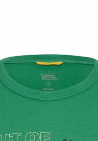 Grøn økologisk bomulds T-shirt med rund halsudskæring, med en gul label indeni og hvid teksttryk. Glat tekstur og minimalistisk design.