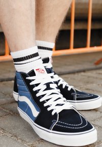 Høje sneakers med blå og sorte suede-paneler, hvide snørebånd og gummisåler. Har klassisk sidestribe og kontraststing detaljer.