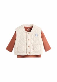 Beige quilted baby vest with buttons over a rust-colored long-sleeve ribbed shirt, featuring a small blue smiley face on the chest.