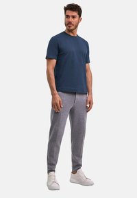 Granatowy bawełniany t-shirt w zestawieniu z jasnoszarymi dresami z bocznym paskiem, uzupełnionymi białymi sneakersami. Luźny krój i wygodny design.