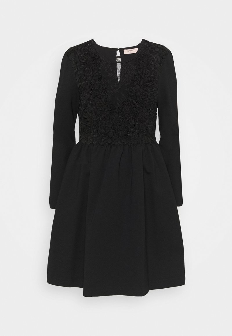 Robe noire à manches longues avec des détails en dentelle sur le corsage, un léger décolleté en forme de goutte, une jupe évasée et un col rond.