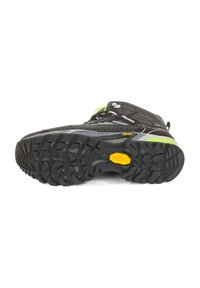 Schwarzer Wanderschuh mit einer strukturierten Gummisohle, versehen mit einem Vibram-Logo. Enthält reflektierende Akzente, Schnürsenkel und ein schlankes Design.