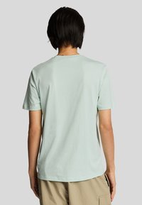 T-shirt in cotone verde chiaro con scollatura rotonda e maniche corte, caratterizzato da una texture liscia e una vestibilità comoda. Nessun motivo visibile.