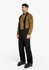 Black ski pants with adjustable straps and a matching brown fleece top. Pants feature a relaxed fit and durable fabric, designed for winter activities.