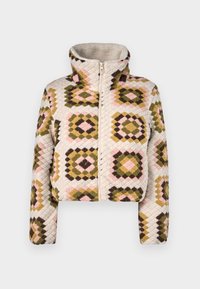 Beskurad zip-up jacka i krämfärg med ett texturerat lapptäckemönster i olivgrönt, rosa och bruna diamanter. Hög krage för extra skydd.