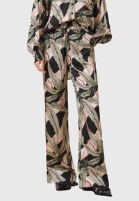 Pantaloni di satin neri con un grande motivo a foglia in verde e rosa. Fit comodo con vita elasticizzata. Abbinati a un top coordinato.