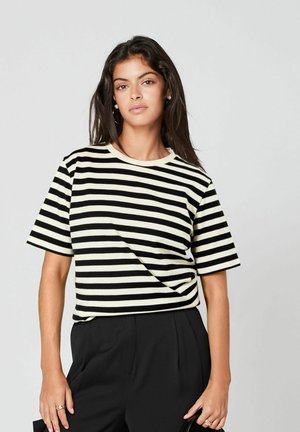 Black and cream striped short-sleeve t-shirt with a round neck and soft texture, paired with high-waisted black trousers.