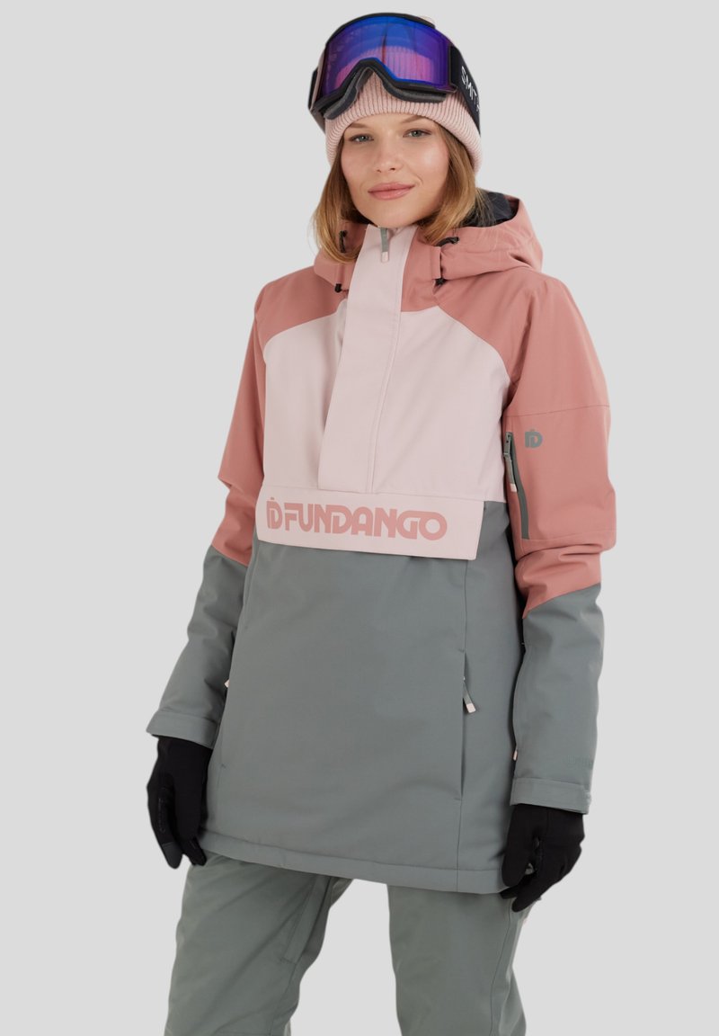 Rosa och grå snöjacka med hög krage, framdragkedja, logotyp på bröstet och justerbara ärmslut. Bärs med svarta handskar och en mössa.