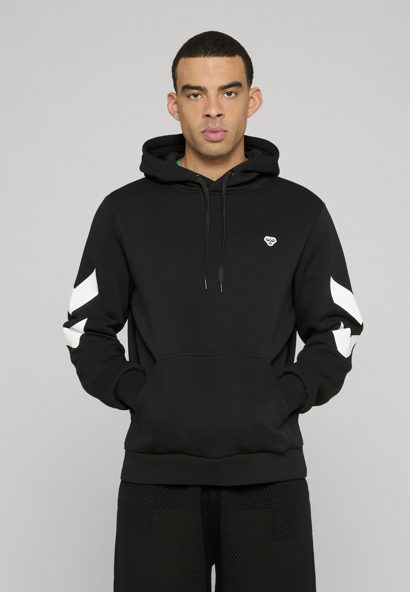 Sweat à capuche noir avec une poche avant, capuche à cordon de serrage et des rayures chevrons blanches sur les manches. Présente un petit logo sur la poitrine.
