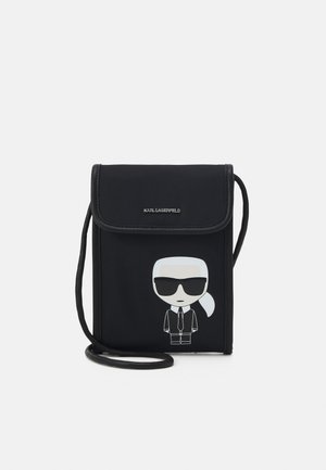 Sac bandoulière noir avec rabat, avec une figure de dessin animé d'un homme aux cheveux blancs, lunettes de soleil et costume sur le devant.