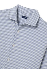 Camicia a quadri azzurro chiaro e bianca con collo appuntito, chiusura con bottoni e tessuto morbido. Etichetta con scritto "PIOMBO."