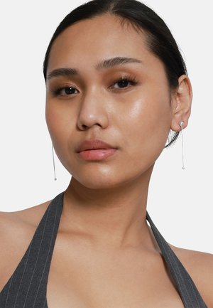 Silberne Tropfohrringe mit minimalistischer Gestaltung, featuring einer dünnen Kette und kleinen sphärischen Akzenten, vor einem neutralen Hintergrund.
