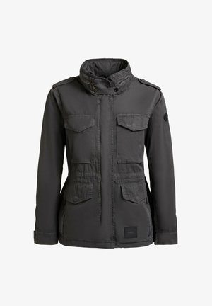 Giacca stile militare grigio scuro con collo alto, quattro tasche con pattina, chiusure con zip e bottoni a pressione, e una toppa sulla manica sinistra.