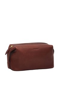 Brown leather toiletry bag with a smooth texture, rectangular shape, top zipper closure, and subtle embossed branding on the front.