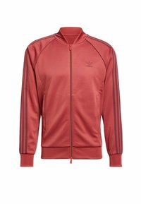 Rote Sportjacke mit Reißverschluss, geripptem Kragen und Bündchen. Verfügt über drei dunkle Streifen entlang der Ärmel und ein dezentes Logo auf der Brust.