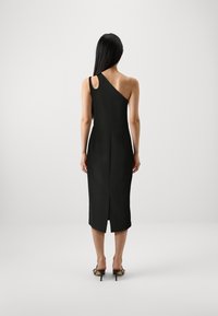 Svart, asymmetrisk midi-kjole med én skulderrem, tettsittende design, bakre splitt for bevegelse, glatt tekstur og minimalistisk stil.