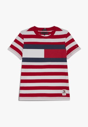 Bavlněné tričko s červenými a bílými horizontálními pruhy, s modrým obdélníkovým panelem přes hruď a logem na spodní části.