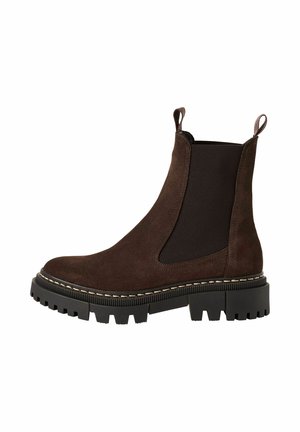 Botte Chelsea en daim brun foncé avec semelle épaisse à crampons noire, panneaux latéraux élastiques et languettes à la cheville.