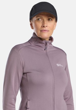 Light purple long-sleeve top with a high collar, zip closure, and side pockets. Features a textured fabric and Jack Wolfskin logo on the chest.