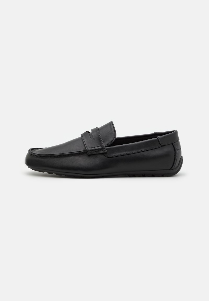 Mocassin en cuir noir avec lanière penny, couture moc toe, et semelle en caoutchouc, présenté en vue latérale sur un fond uni.