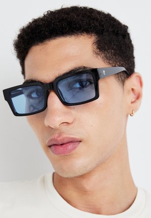 Schwarze rechteckige Sonnenbrille mit blauen Gläsern, ausgestattet mit einem dicken Rahmen und feinen Hardware-Details an den Bügeln.