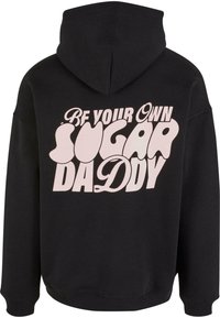 Felpa con cappuccio nera caratterizzata da una grande stampa di testo stilizzata in rosa che dice "SII IL TUO STESSO SUGAR DADDY" sul retro. Tessuto morbido, vestibilità casual.