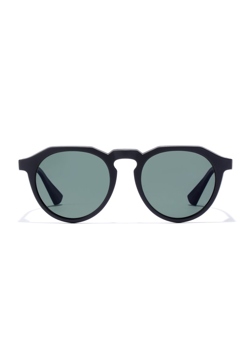 Ochelari de soare cu ramă rotundă din material plastic negru, cu lentile verzi tintate și un design unghiular. Prezintă detalii subtile pe ramă.