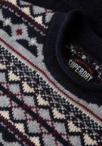 Marineblauwe trui met een Fair Isle patroon in grijs, crème en bordeauxrood, voorzien van een geribde ronde hals en een label met de tekst "Superdry."