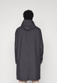 Lång, mörkgrå kappa med huva, med en elegant design, slät textur och sidofickor, sedd bakifrån.