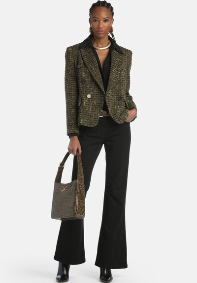 Tweed double-breasted blazer with gold and black tones, paired with a black shirt and flared pants. Brown crocodile-textured handbag.