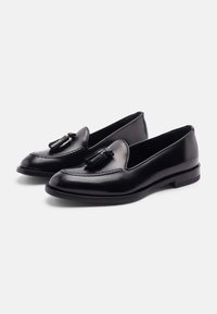 Schwarze Lederloafers mit Quastenakzenten, runder Zehenform, sichtbaren Nähten und glatter Textur. Verfügt über einen niedrigen Absatz und ein Slip-On-Design.